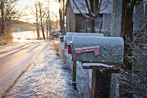 Winter sunrise on a rural road in Mahone Bay Nova Scotia showing mailboxes and a lake.