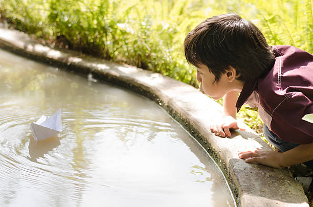 istock Little boy enjoy blowing paper boat 531643153