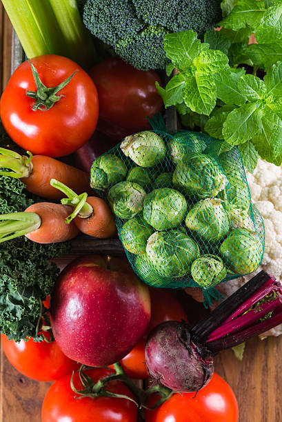 This food photography showcases the beautiful texture and color contrast of tomatoes, leafy greens, and cabbage buds. great for culinary and nutrition content