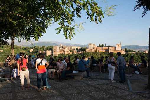 Granada, Spain - June 9, 2014: People gather at the Mirador San Nicolás for the view of the Alhambra, a palace and fortress complex in Granada, Spain.