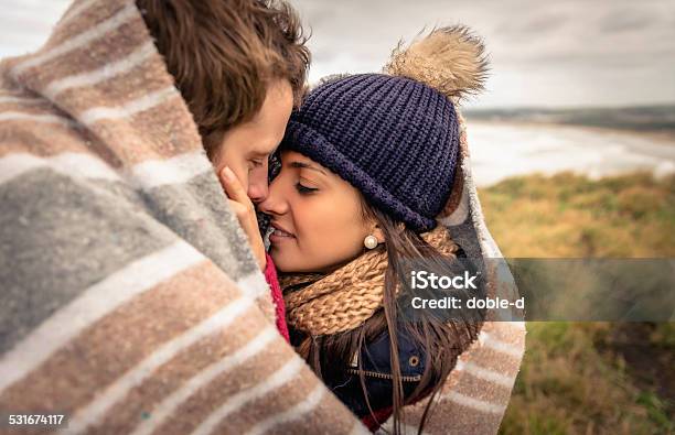 Young Couple Embracing Outdoors Under Blanket In A Cold Day Stock Photo - Download Image Now