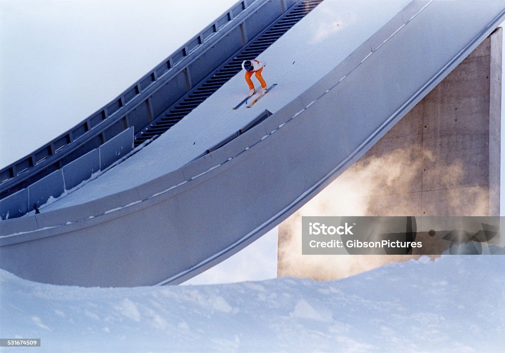 Nordic Ski Jumper A male ski jumper crouches in position and gets ready to leap off a nordic ski jump. Ski Jumping Stock Photo