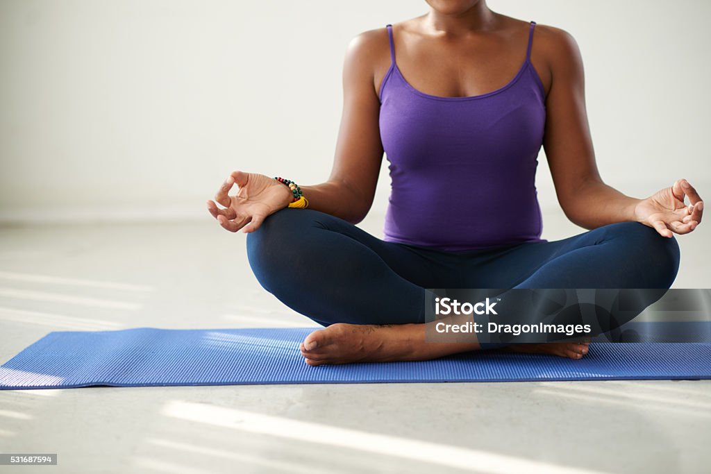 Lotus position Cropped image of woman practicing yoga indoors African Ethnicity Stock Photo