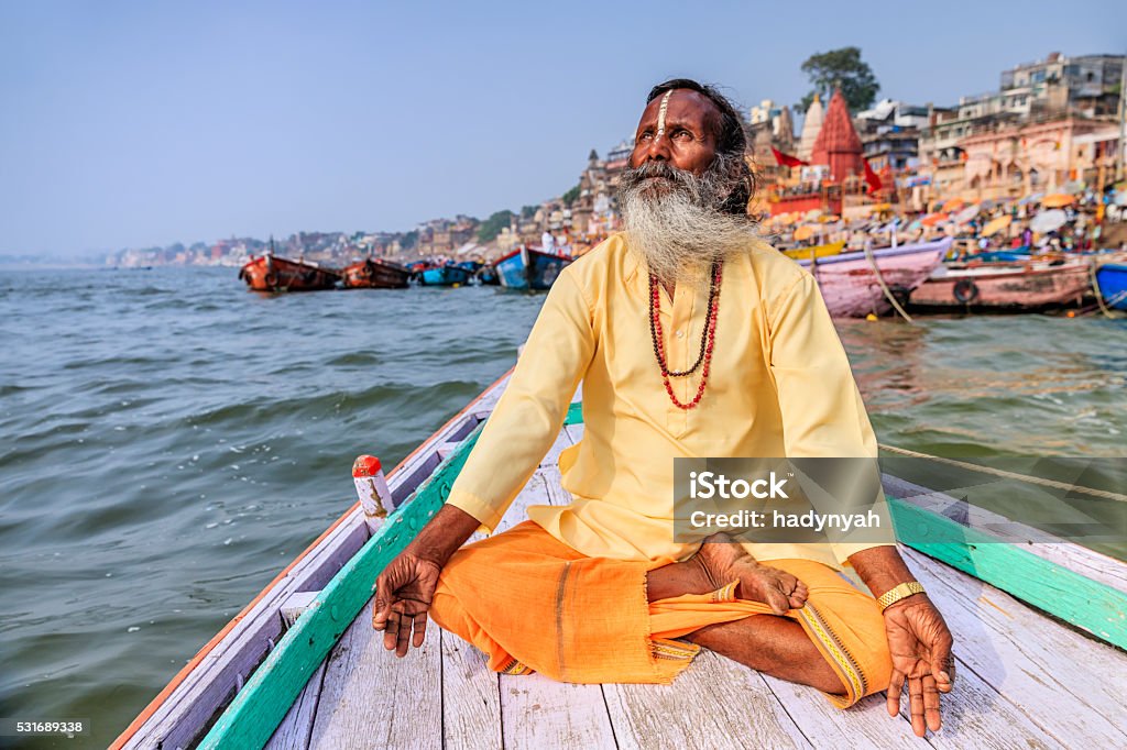 Sadhu is meditating in boat on Holy Ganges River, Varanasi - Royaltyfri Indien Bildbanksbilder