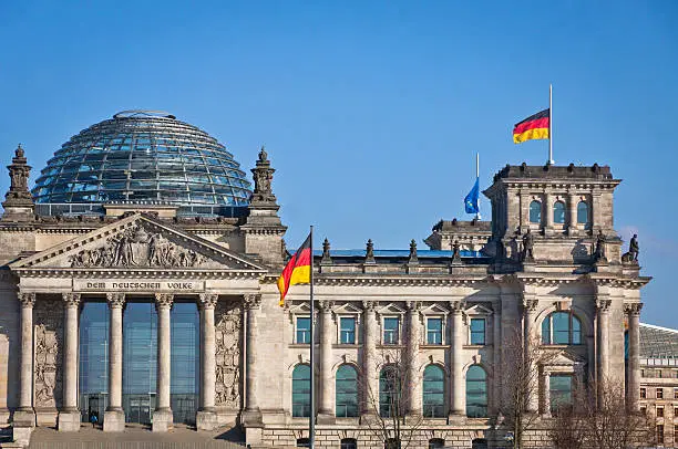 Flags of Federal Republic of Germany waving in front of the German parliament building (Reichstag) in Berlin, Germany