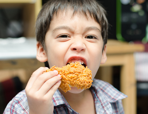 Little boy eating fried chicken