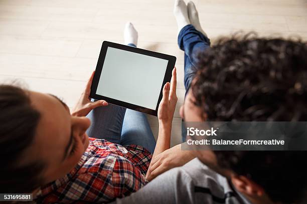Pareja Joven Sentada En La Sala De Estar Y El Uso De Tablet Foto de stock y más banco de imágenes de 2015