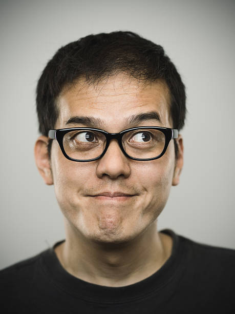 Portrait of a young japanese man looking up. Studio portrait of a japanese young man looking up. The man is around 35 years and has black hair, glasses and casual clothes. Vertical color image from a medium format digital camera. Sharp focus on eyes. real young asian guy portrait looking upwards stock pictures, royalty-free photos & images