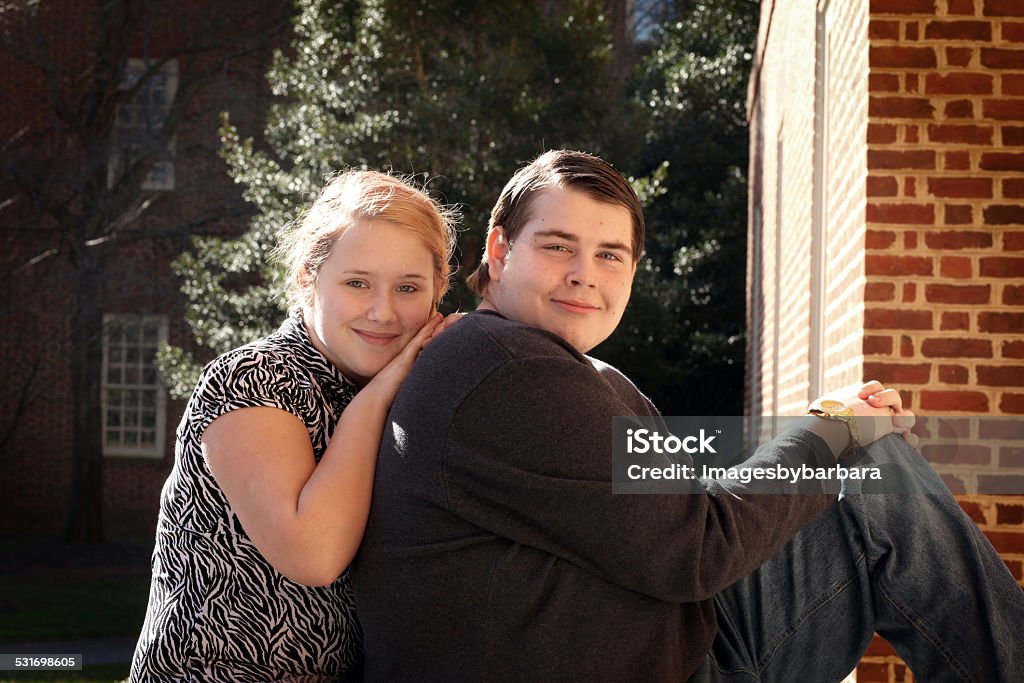 Sister showing her Autistic brother some love and affection. Sister leaning on her Autistic brother's back. Autism Stock Photo