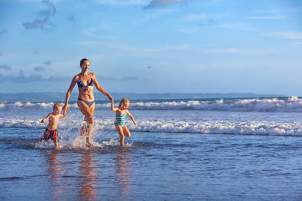 feliz familia de diversión en la playa con olas al atardecer - bikini surfboard women surfing fotografías e imágenes de stock