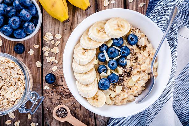 Breakfast: oatmeal with bananas, blueberries, chia seeds and almonds Breakfast: oatmeal with bananas, blueberries, chia seeds and almonds. Top view oats food stock pictures, royalty-free photos & images