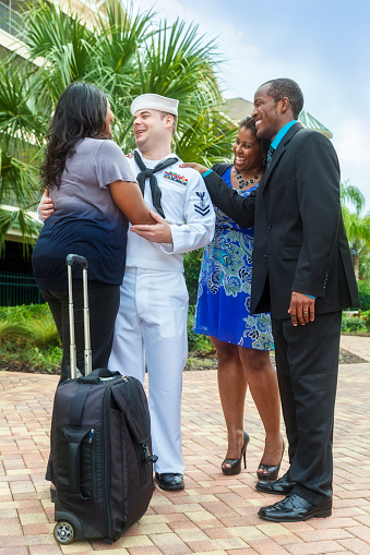 A sailor returns home from active duty and is greeted by family and friends.