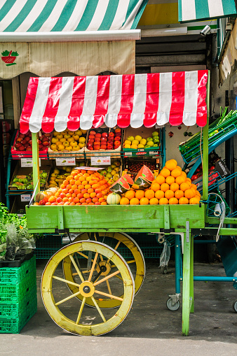  Paris, France - May 25, 2014: An old wooden vendors cart with a red awning is piled high with an assortment of fresh fruit outside a shop in Paris.