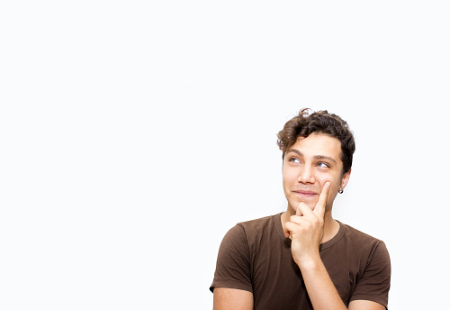 Portrait of thinking young man over white background. Thinking young man looking up isolated on white. Horizontal composition. Studio shot. There is copy space on left side of image for your text or extra image.