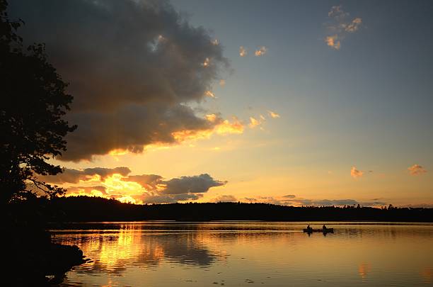 canoagem ao pôr do sol sobre o lago de floresta - boundary waters canoe area imagens e fotografias de stock
