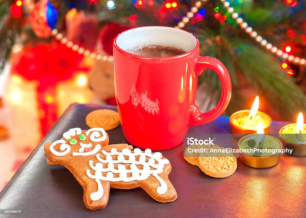 Sheep shape gingerbread with cup of coffee on christmas background. Sheep shape gingerbread cookie with cup of coffee on illuminated christmas tree background. Festive indoors still-life. 2015 Stock Photo