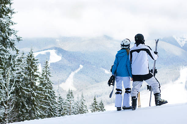 Happy couple standing on a mountain top.Couple skiing and snowboarding outside in the mountains.