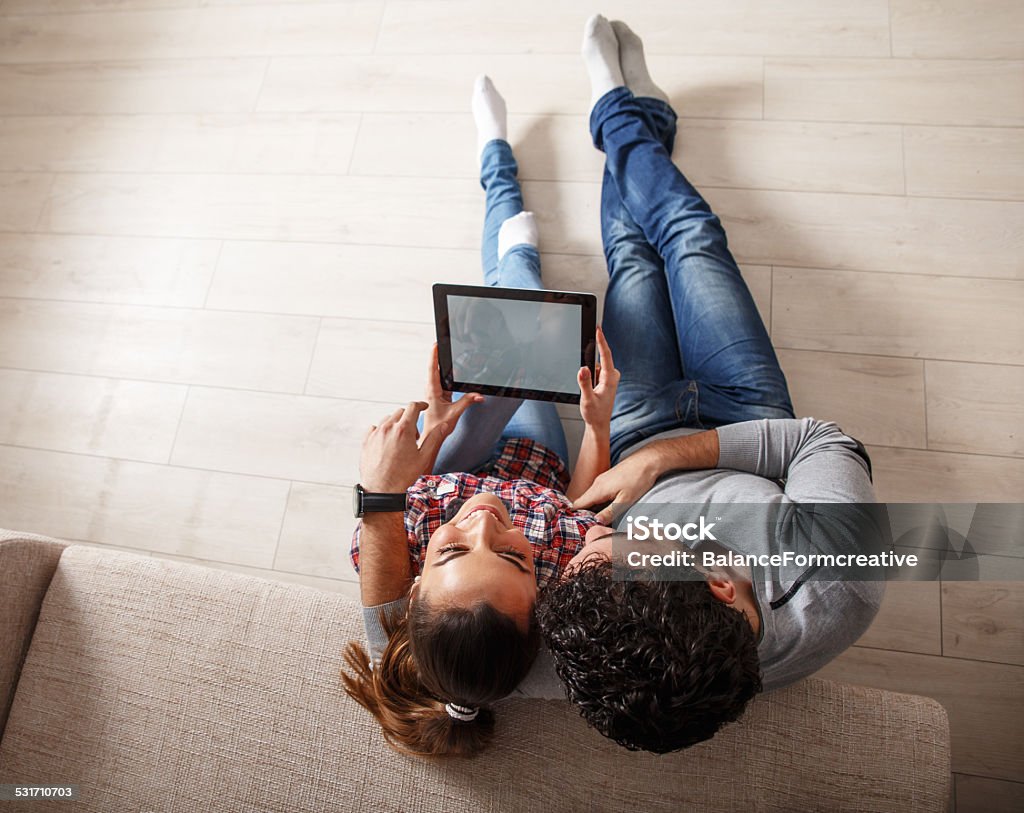 Pareja joven sentada en la sala de estar y el uso de tablet - Foto de stock de Adulto joven libre de derechos