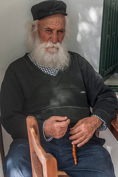 Alerobello, Italy - May 10, 2024.  Senior man sitting in front of his souvenir-shop in the  historic and monumental  city of Alberobello.