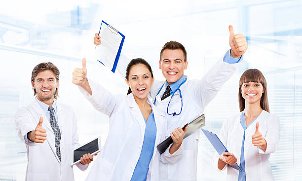 team medico medico felice sorriso tenere il pollice-up - healthcare and medicine smiling group of people lab coat foto e immagini stock