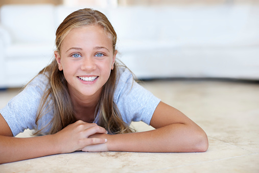 Portrait of a young girl lying on the floor at home