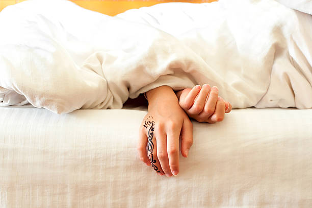 Sleeping little child hands on white bed linen. Indoors closeup. Little sleeping child hands with tattoo on white bed linen. Indoors closeup. wrist tattoo stock pictures, royalty-free photos & images