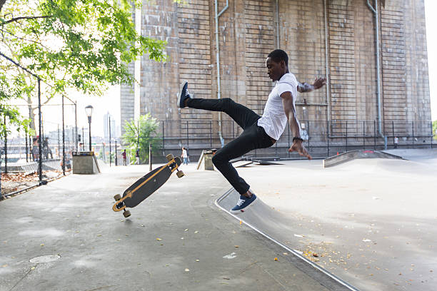 schwarzer junge skaten im park und das falling down - longboard skating stock-fotos und bilder