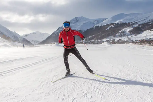  A man cross-country skiing in front of winter landscape.