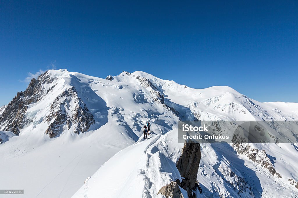 View of the Alps from Aiguille du midi Group of Climbers Going up at Mont Blanc Summit in Chamonix, France. They are walking with backpack on this sunny day with clear sky and the Mont Blanc mountain summit is visible in the background. 2015 Stock Photo