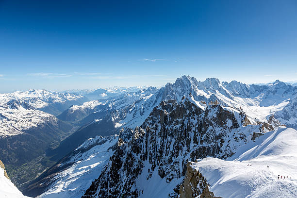 Deep blue high altitude skies and bright sun flaring over the glistening white glaciers, jagged pinnacles and panoramic wilderness summits of this pristine mountain environment. ProPhoto RGB profile for maximum color fidelity and gamut.