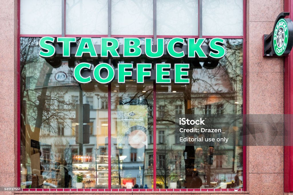 Starbucks Coffee in Prague with reflection in window during day Prague, Czech Republic - January 7, 2015: Starbucks Coffee store in the main downtown area in Prague attracts many foreign and local visitors due to its location. Starbucks is very popular in this part of Europe, even with average prices higher than other local or regional similar chain stores. There are six Starbucks Coffee stores in the Prague downtown. 2015 Stock Photo