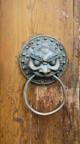 A close-up of a doorknob and door keyhole on a gray background during the daytime in a room in Central Java.