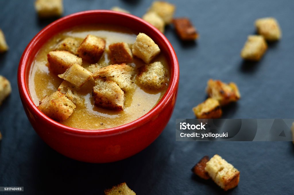 Pumpkin soup with homemade croutons in a small, red bowl Crostini Stock Photo