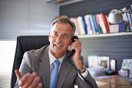 Shot of a mature businessman looking pleased while talking on the phone in his officehttp://195.154.178.81/DATA/istock_collage/0/shoots/785086.jpg