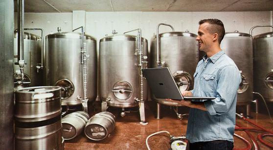 Smiling brewmaster working with laptop in industryhttp://www.twodozendesign.info/i/1.png
