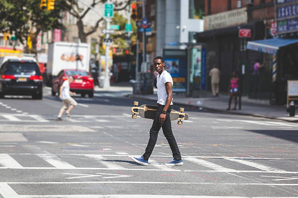 istock Black Boy Walking in the City Holding Longboard 531756415