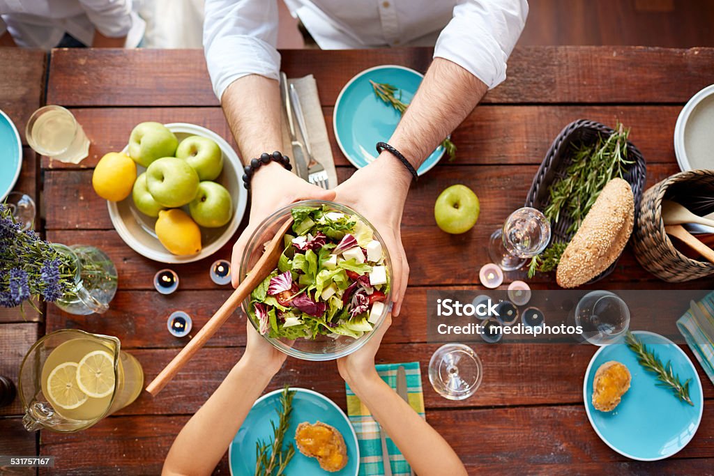 Vegetarian dinner Man giving a bowl with healthy salad to his wife at dinner Passing - Giving Stock Photo