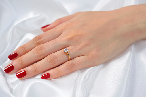 Wedding ring on hand of bride on white cloth