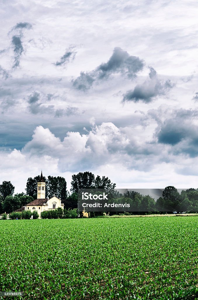 cornfield davanti a una chiesa nel cielo nuvoloso - Foto stock royalty-free di 2015