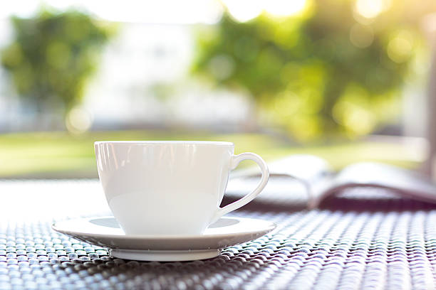 istock Coffee cup with book on blur green nature background 531769413