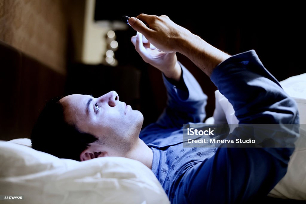 Hombre usando el teléfono en la cama - Foto de stock de Caer libre de derechos