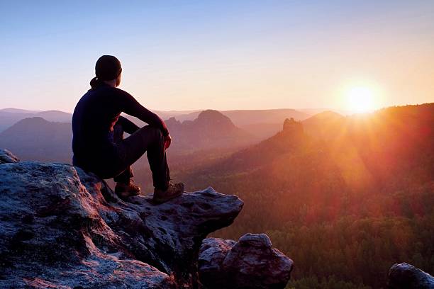 istock Tired hiker in black trousers, jacket and cap on cliff 531771974