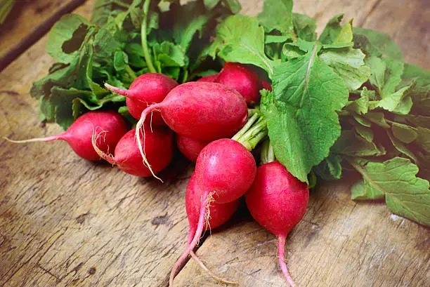 Photo of Fresh radishes on old wooden table