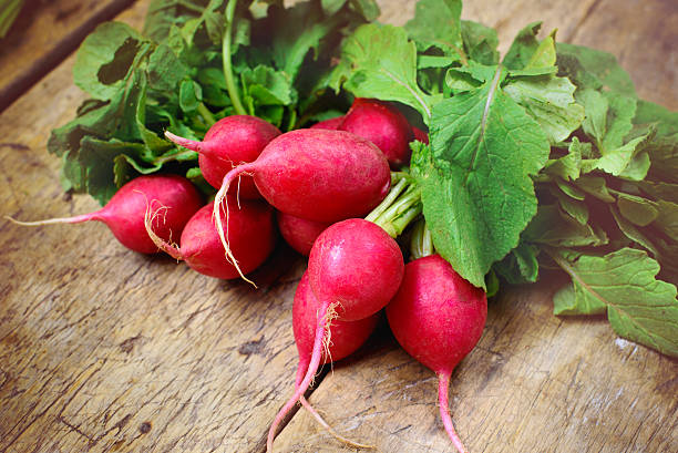 свежие radishes на старый деревянный стол - radish ст�оковые фото и изображения