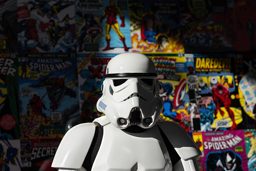 Madrid, Spain - November 30, 2014: Head shot of a white Imperial Stormtrooper action figure against a colorful wall, covered with old Marvel Super-heroes comic books (Spiderman, Daredevil, X-Men, Iron Man...). The Imperial Stormtroopers are fictional soldiers from George Lucas' Star Wars universe. They are the main ground-force of the Galactic Empire, impossible to sway from the Imperial cause. They wear imposing white armor, which offers a wide range of survival equipment and temperature controls to allow the soldiers to survive in almost any environment. 