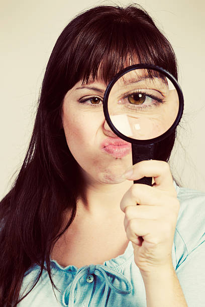 istock Young woman looking through magnifying glass scowls grumpily 531774727