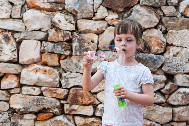 istock lovely little girl blowing soap bubbles 531774855