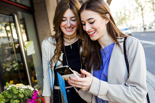 istock Two beautiful young women using mobile phone in the street. 531775644