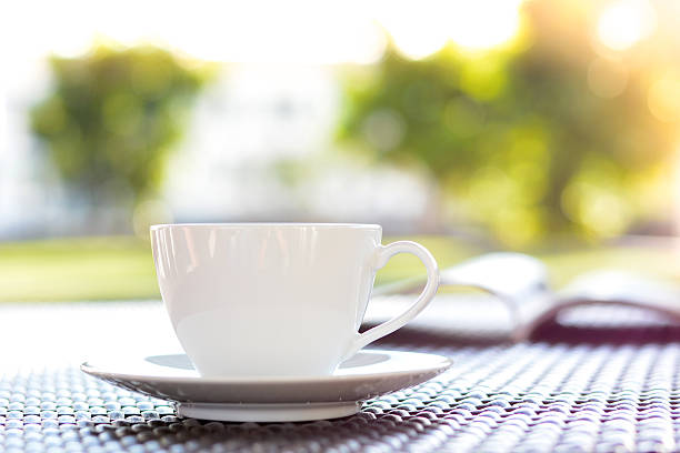 istock Coffee cup with book on blur green nature background 531775703