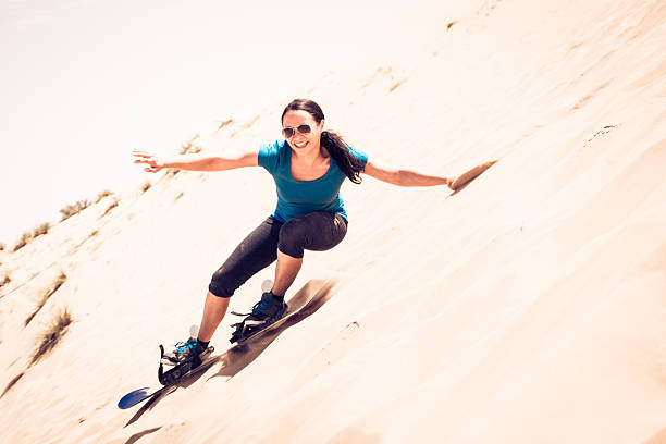 tourist sandboarding in the desert stock photo